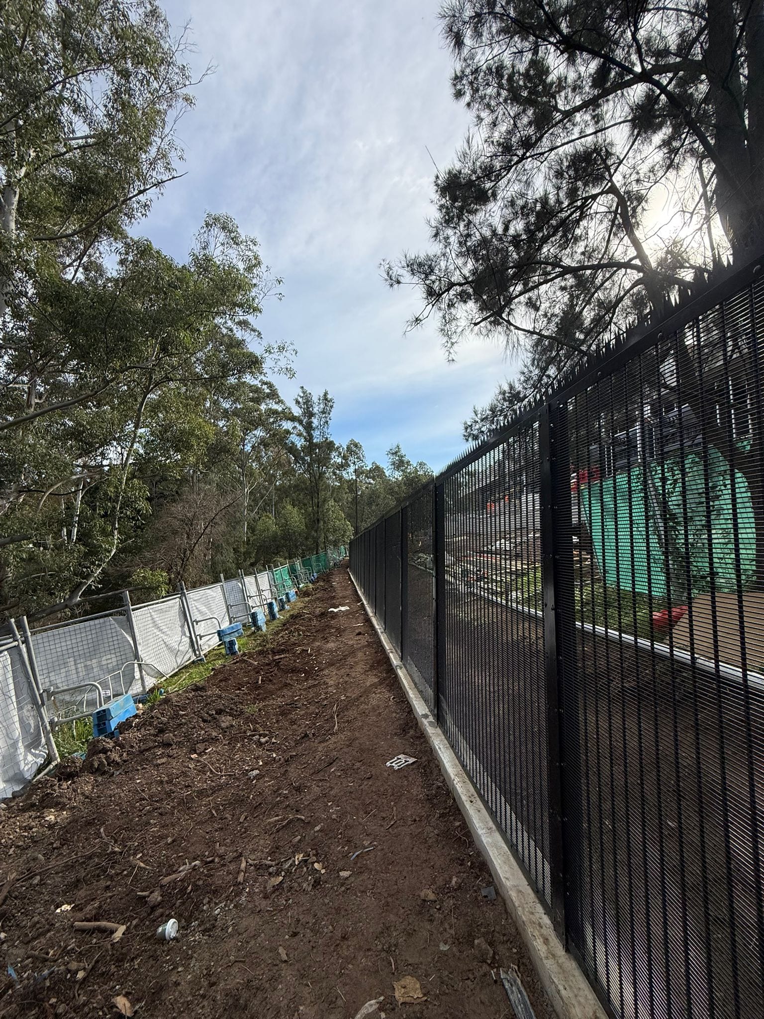 Black 358 anti-climb mesh perimeter along a bushland boundary, July 2026